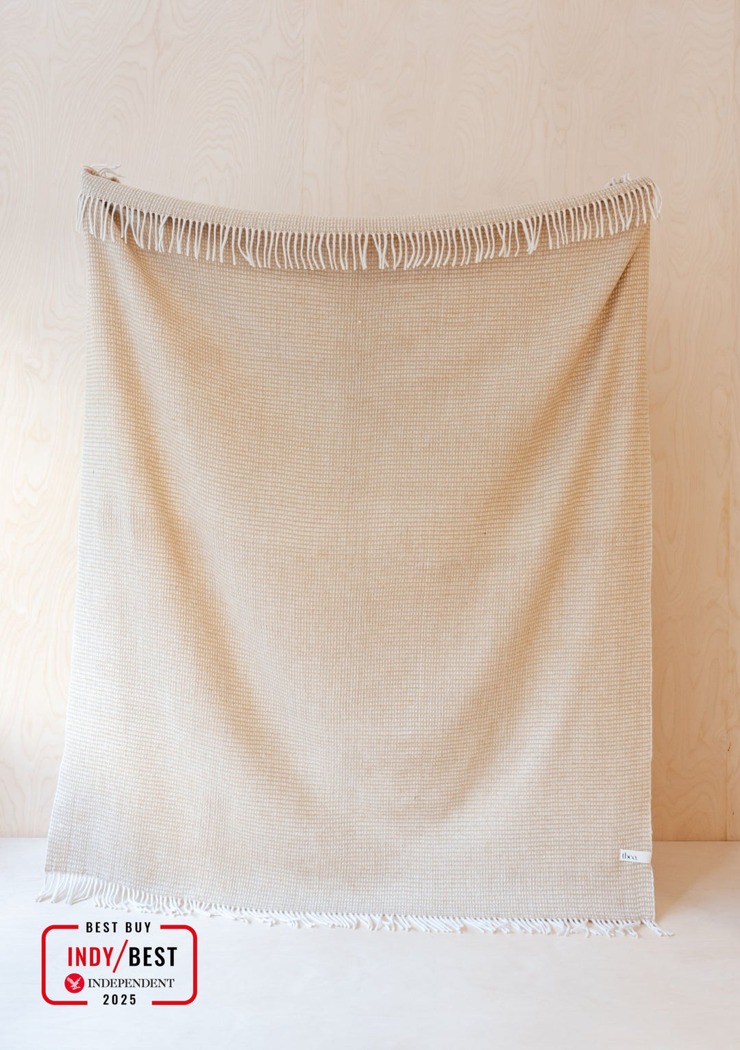 TBCo Recycled Wool Blanket in Neutral Waffle displaying textured weave pattern with fringed edges on beige background