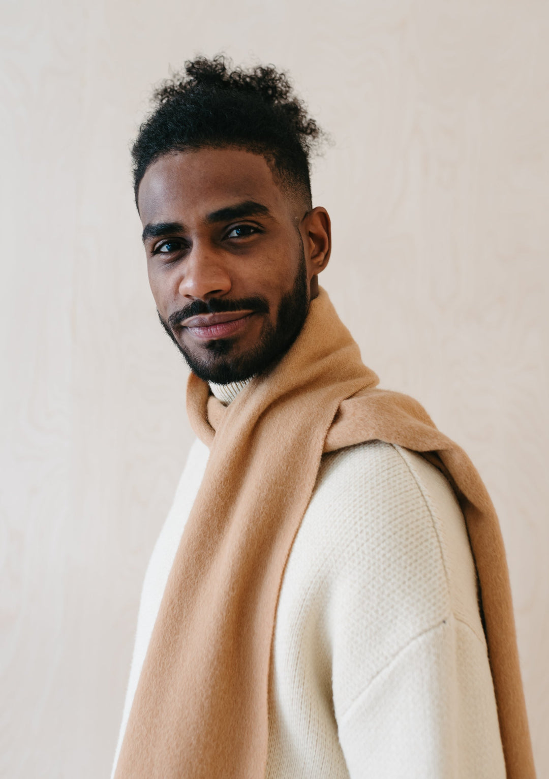 Luxurious TBCo Men's Cashmere Scarf in Camel styled casually with cream jumper showing soft drape and fringed detail