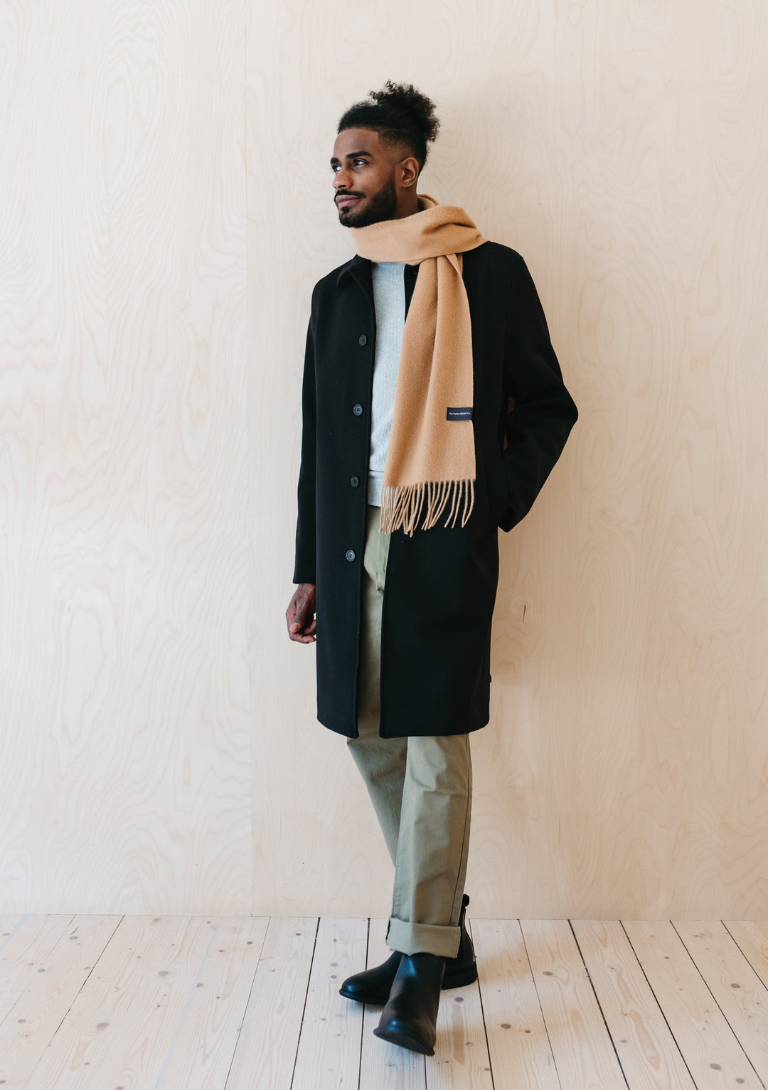 TBCo Men's Lambswool Scarf in Camel styled with black winter coat and light trousers, showcasing fringed design and classic drape