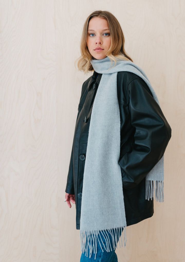 Luxurious TBCo Light Grey Melange Cashmere Scarf with fringe draped elegantly over dark winter coat, showcasing soft texture