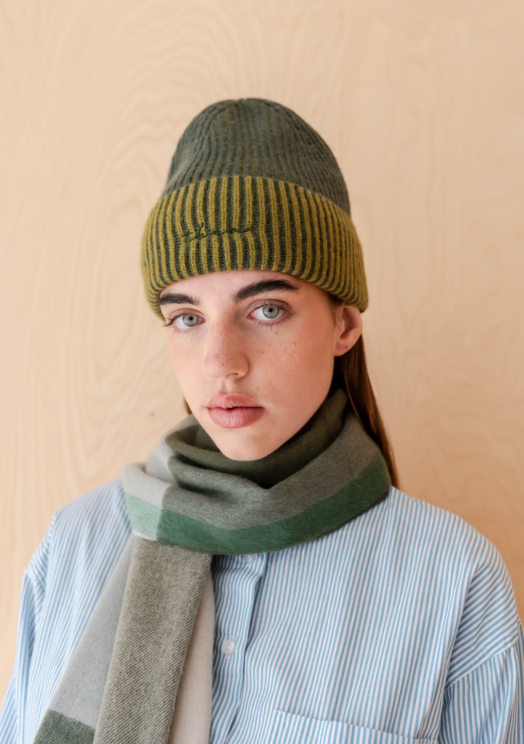 Cashmere & Merino Beanie in Olive Two-Tone by TBCo worn with a striped scarf and light blue shirt.