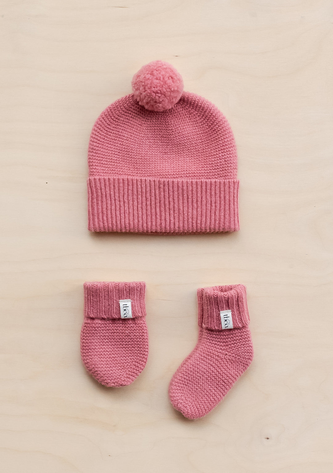 TBCo Merino Wool Baby Accessories Bundle in rose pink featuring knitted beanie with pom-pom, matching mittens and socks