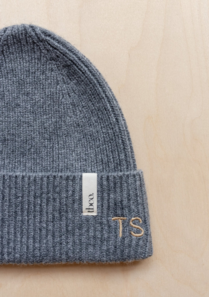 Grey knitted TBCo merino wool baby beanie from Merino Wool Baby Accessories Bundle with branded label and monogram detail