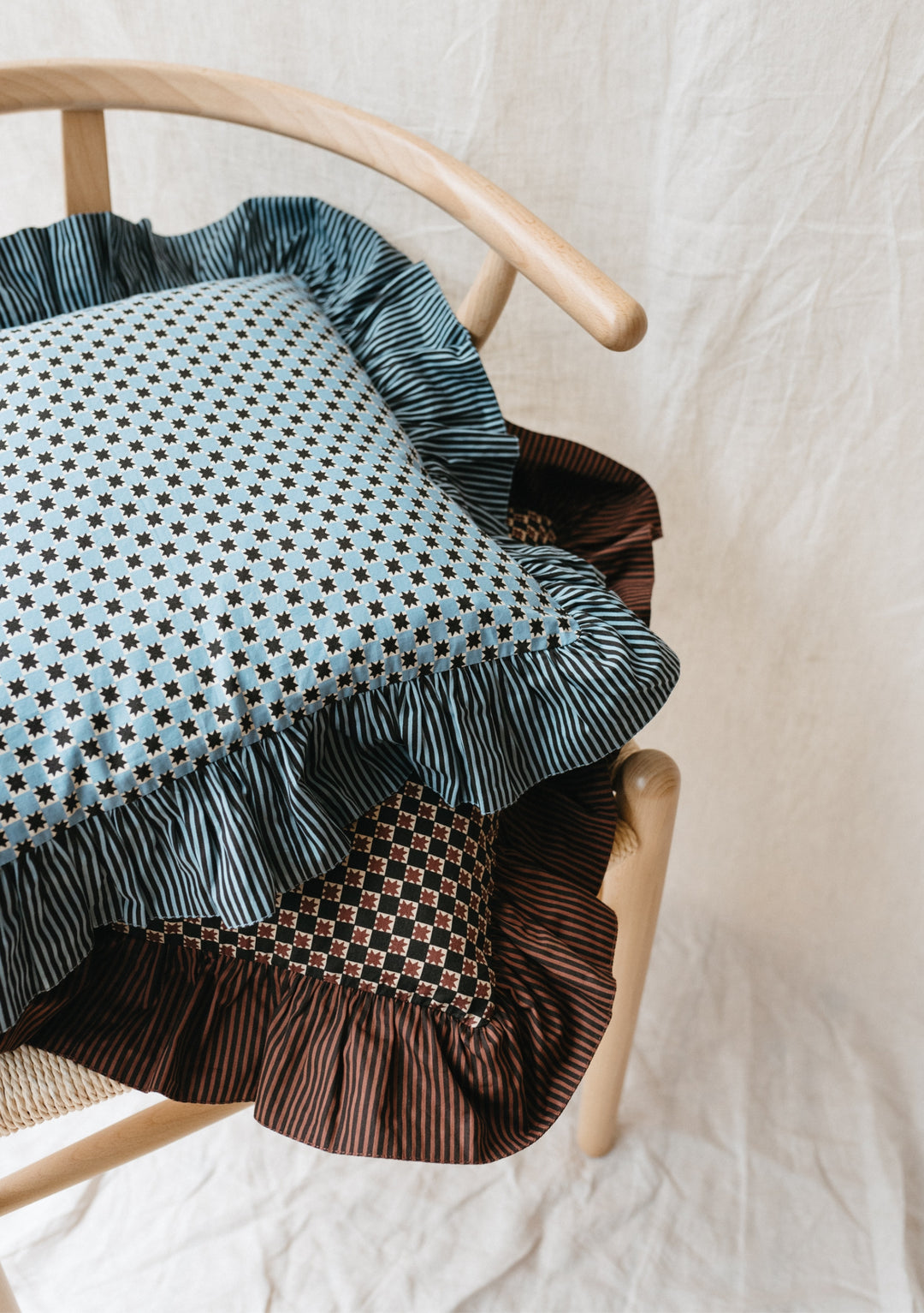 TBCo reversible cotton cushion cover in blue celestial stripe pattern with ruffled edge, displayed on wooden chair
