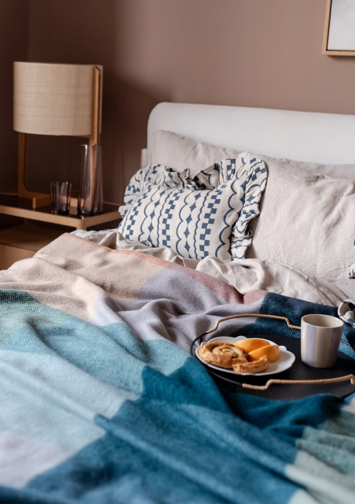 TBCo Cotton Cushion Cover in Navy Ruffle styled on cosy bed with breakfast tray and blue throw blanket