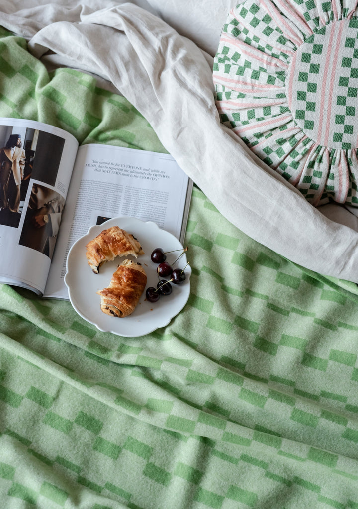 TBCo Cotton Cushion Cover in green and pink stripes with checkerboard pattern, styled with magazine and pastries on white plate