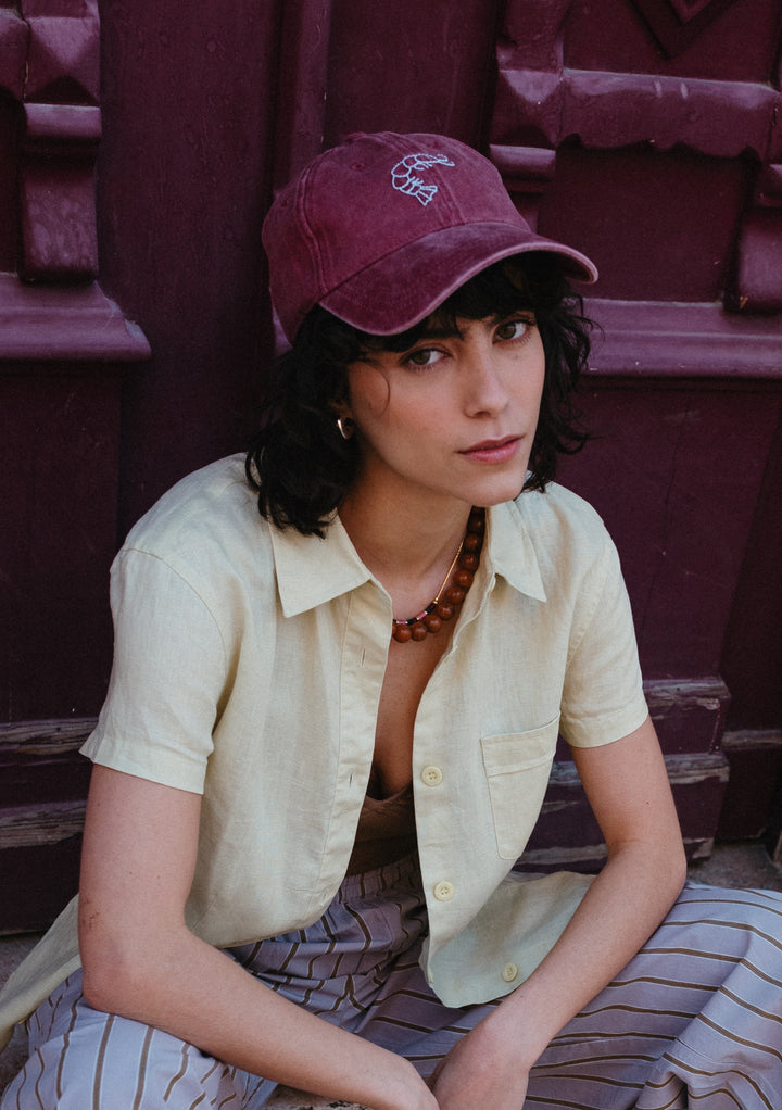 TBCo Recycled Cotton Cap in Shrimp styled with yellow shirt showing embroidered floral detail and adjustable strap design