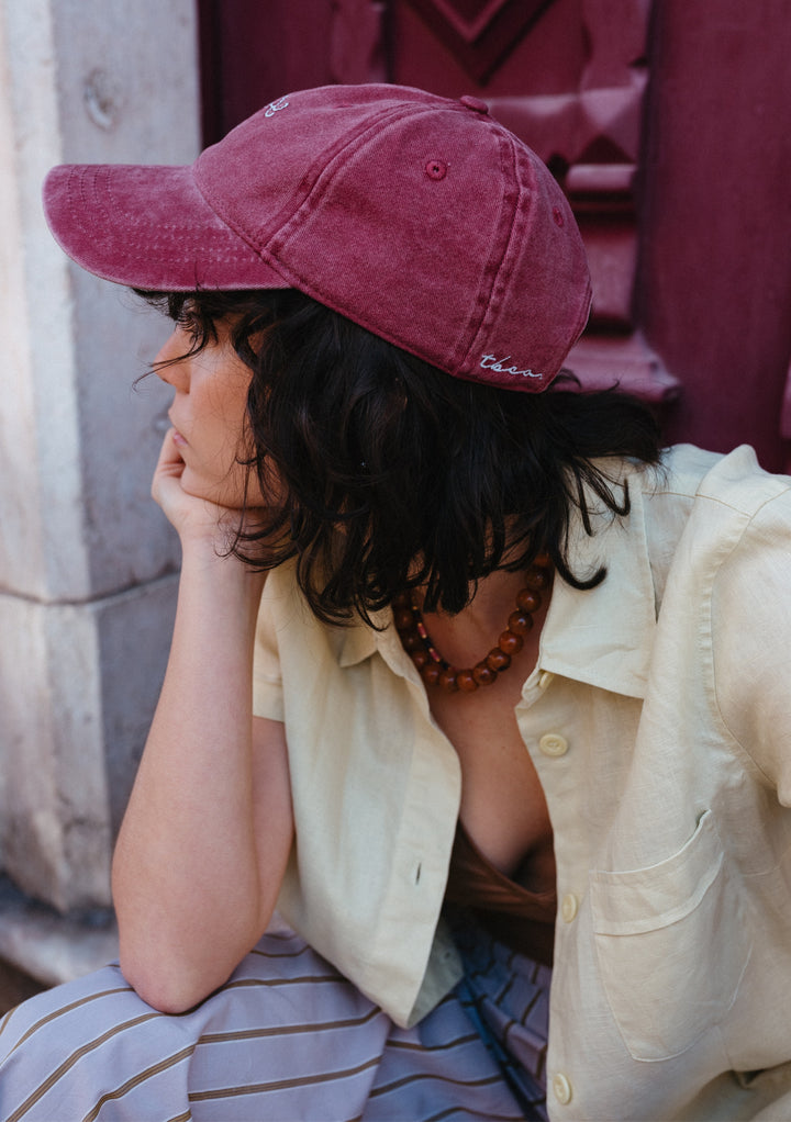 Person wearing TBCo recycled cotton cap in shrimp colour styled with a yellow shirt, showing the adjustable fit and embroidered detail
