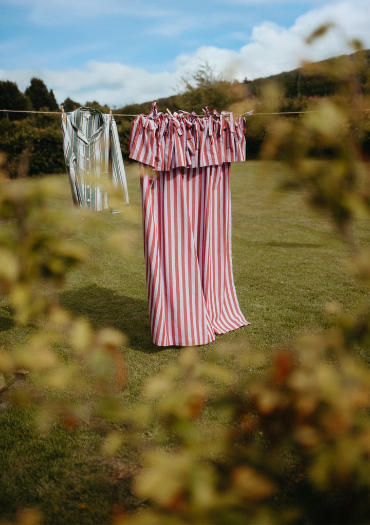 Pair of Cotton Tie-Top Curtains in Lilac Stripe by TBCo hanging outdoors on a clothesline with greenery background