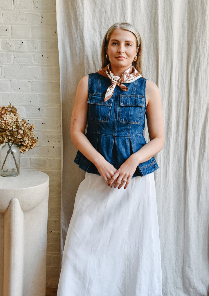 Woman wearing The Artist Series TBCo x Frankie Penwill Cotton Scarf, styled with a denim top and white skirt, near a vase with dried hydrangeas.