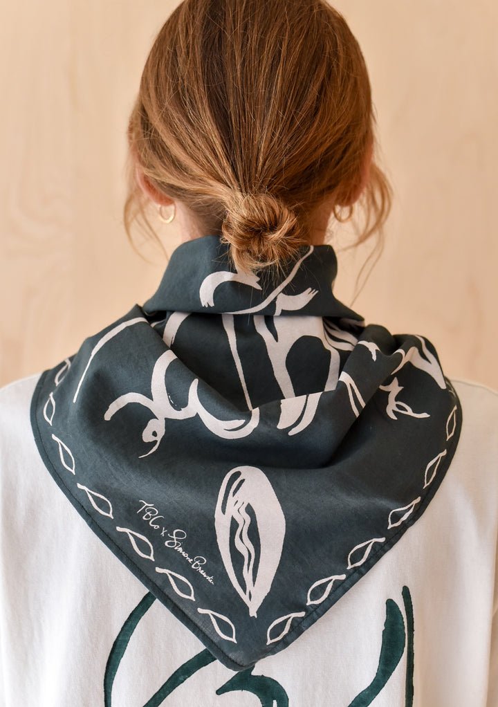 Back view of a person wearing The Artist Series TBCo x Simone Brewster Cotton Scarf, featuring abstract leaf motifs, around their neck.