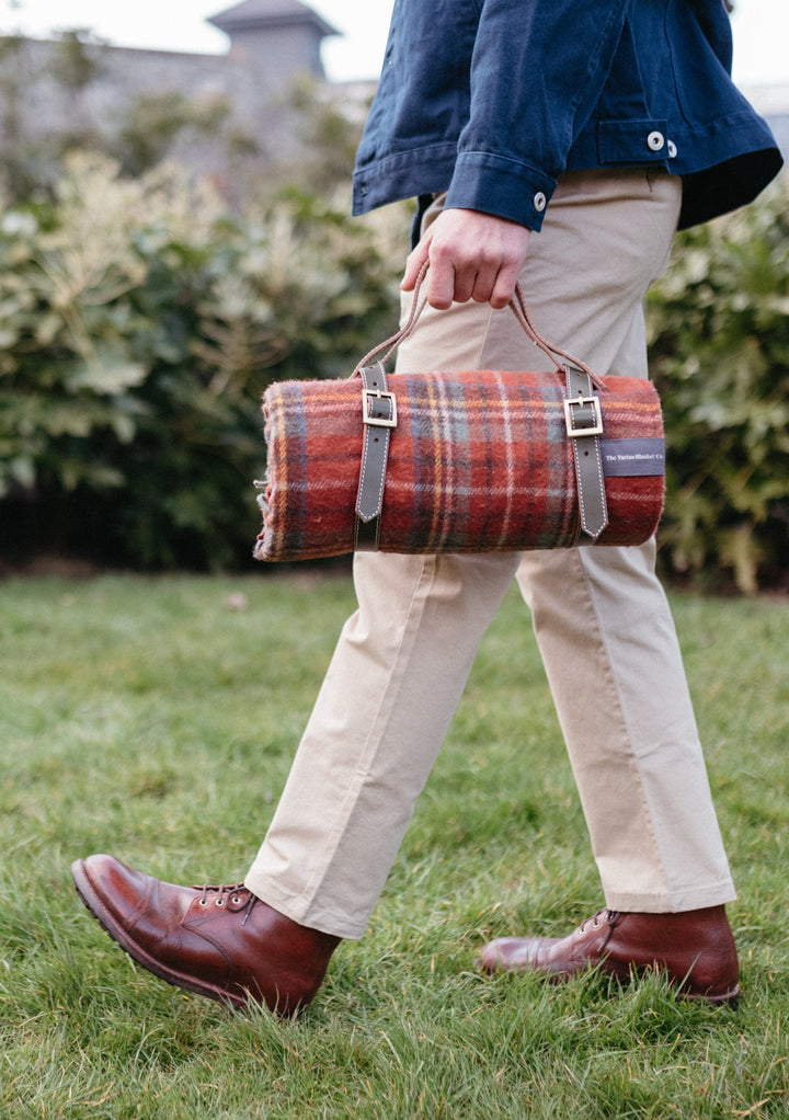 TBCo wool picnic blankets with carrier and should strap arranged in a scenic outdoor setting, showcasing their soft texture and vibrant patterns. Perfect for alfresco dining, relaxing in nature, or stylish outdoor gatherings.