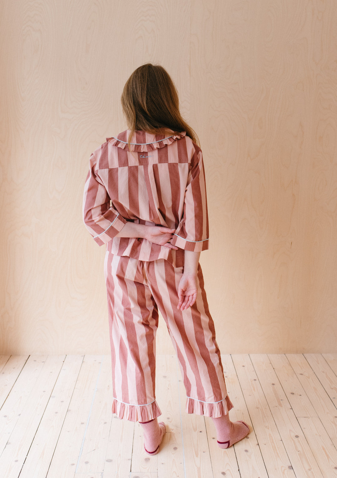 Pink and red striped cotton pyjamas from TBCo, featuring ruffled collar and cropped sleeves, shown from back view with matching slippers