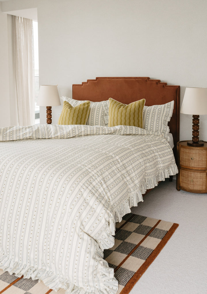 TBCo Cotton Duvet Cover in Navy Ditsy Floral styled on bed with brown headboard, matching table lamps and yellow accent pillows