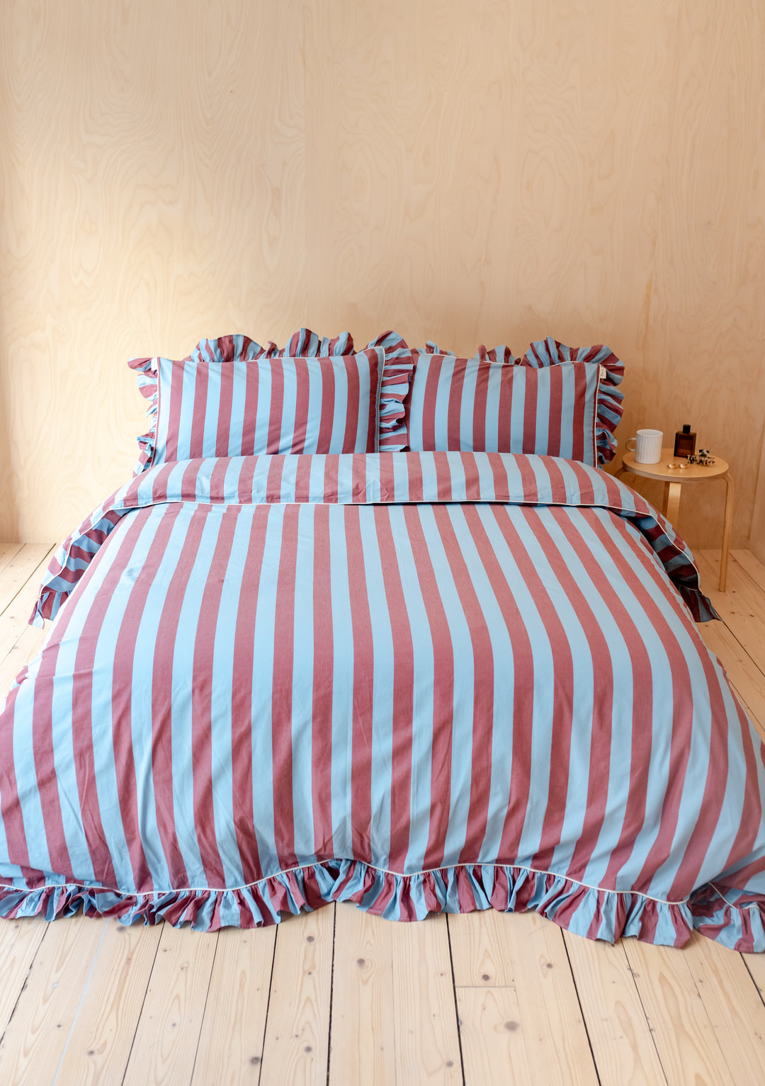 TBCo Cotton Duvet Cover with blue and burgundy stripes and ruffled trim displayed on wooden bed in minimalist bedroom