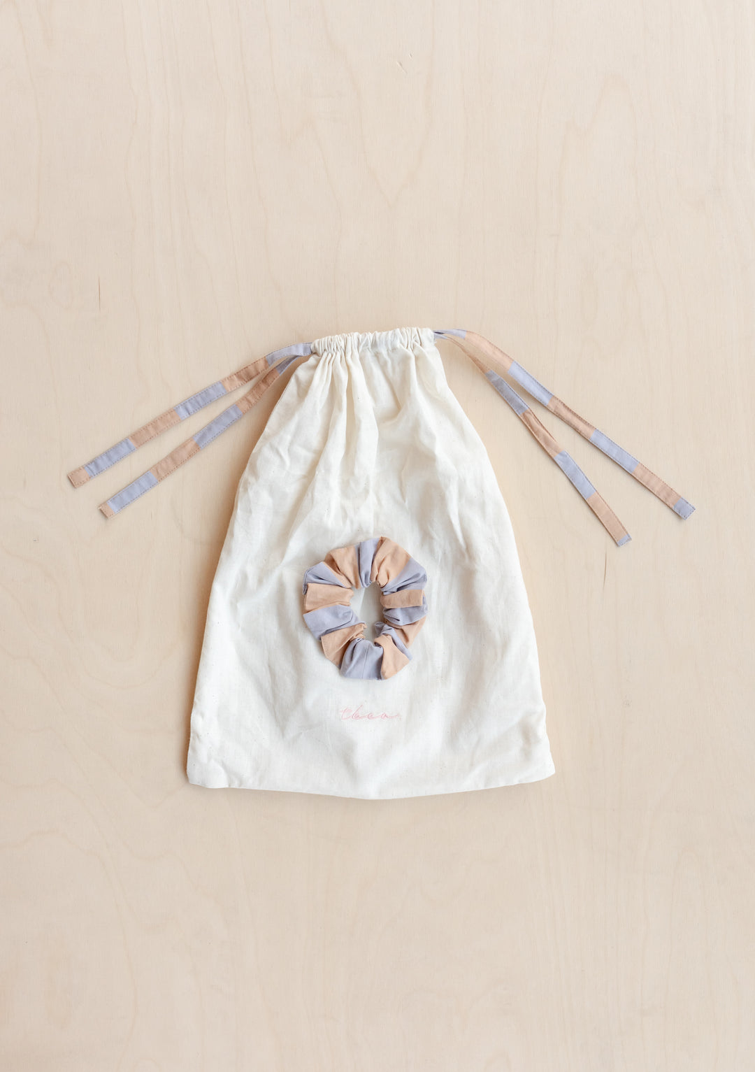 Cotton kids pyjamas by TBCo featuring orange and lilac stripes with drawstring closure and matching scrunchie, laid flat