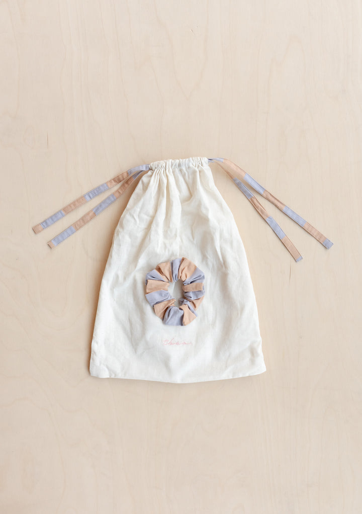 Cotton kids pyjamas by TBCo featuring orange and lilac stripes with drawstring closure and matching scrunchie, laid flat
