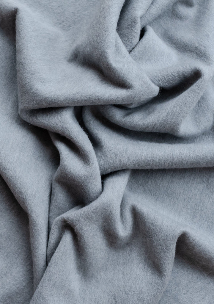Close-up texture of TBCo Lambswool Oversized Scarf in Light Grey Melange showing soft, draped wool fabric with gentle folds