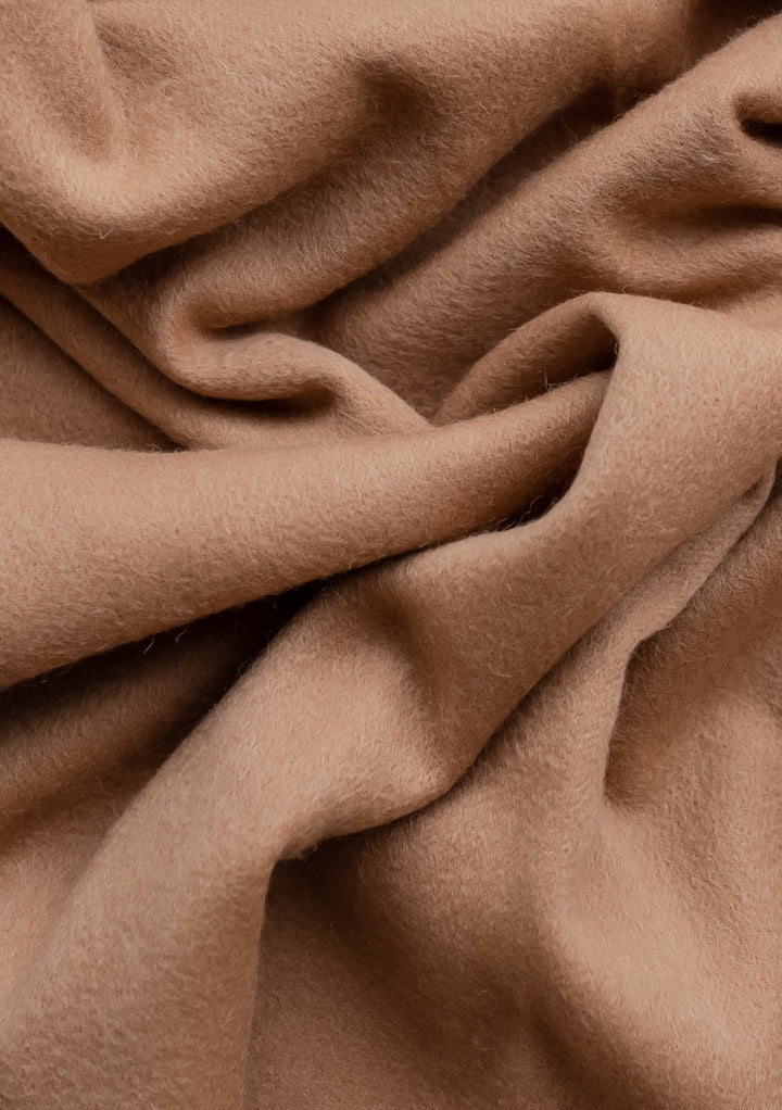 Close-up texture of TBCo Men's Cashmere Scarf in Camel showing luxurious soft folds and rich camel-coloured fabric detail