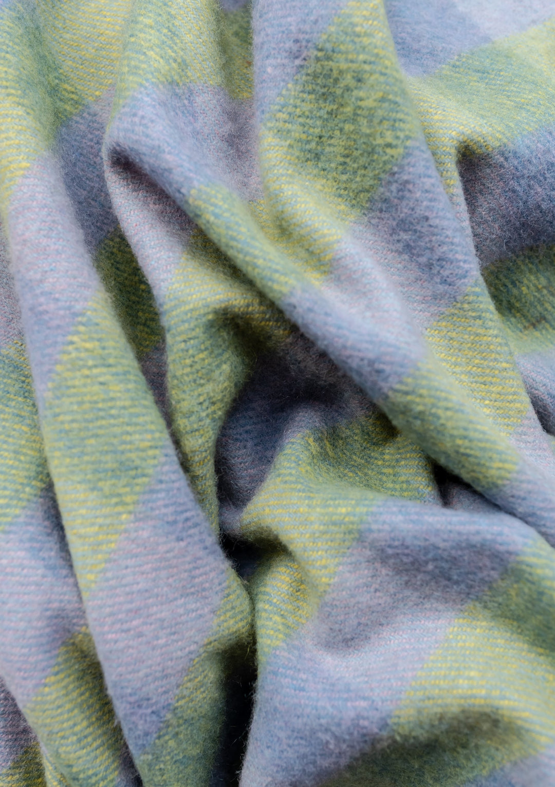 Close-up texture of TBCo Recycled Wool Blanket in green and blue gingham pattern showing soft woven wool fabric with gentle folds