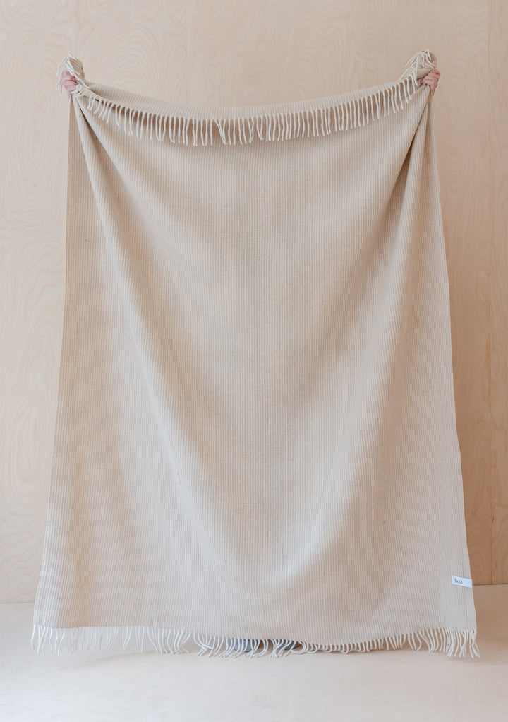 TBCo Recycled Wool Waffle Blanket in camel colour displayed flat with fringed edges against light wooden backdrop