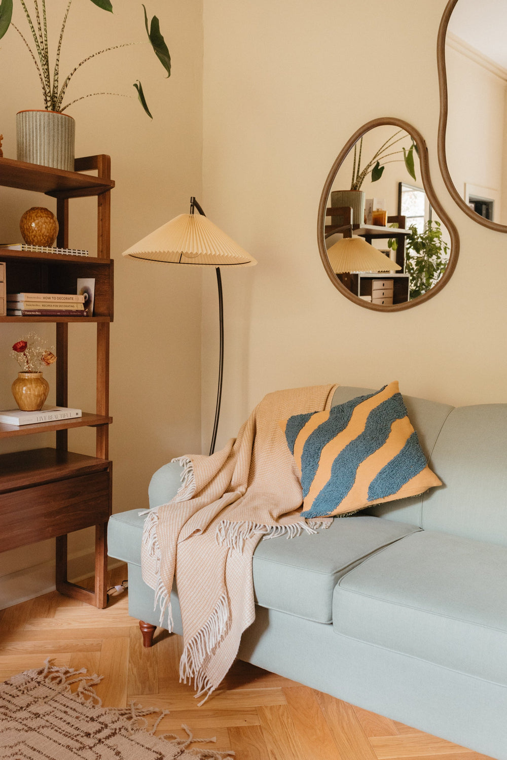 TBCo Recycled Wool Blanket in Neutral Waffle draped over light blue sofa in cosy living room with wooden shelves and curved mirror