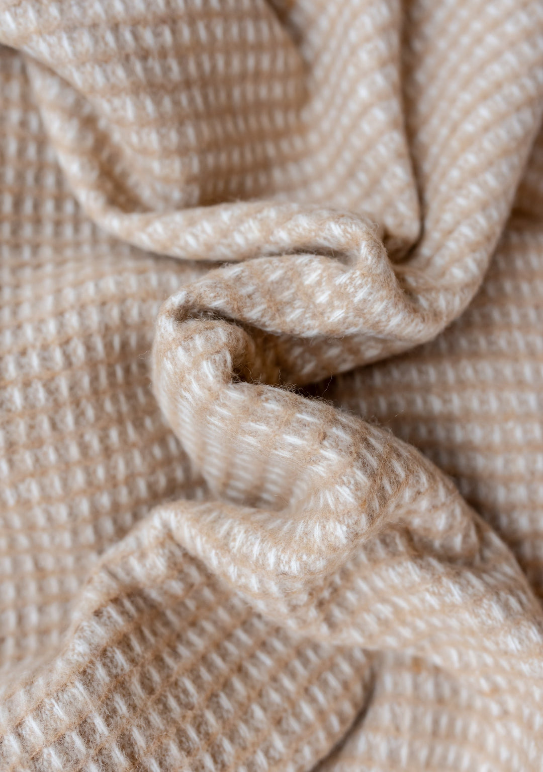 Close-up texture detail of TBCo Recycled Wool Blanket in Neutral Waffle showing soft beige waffle weave pattern