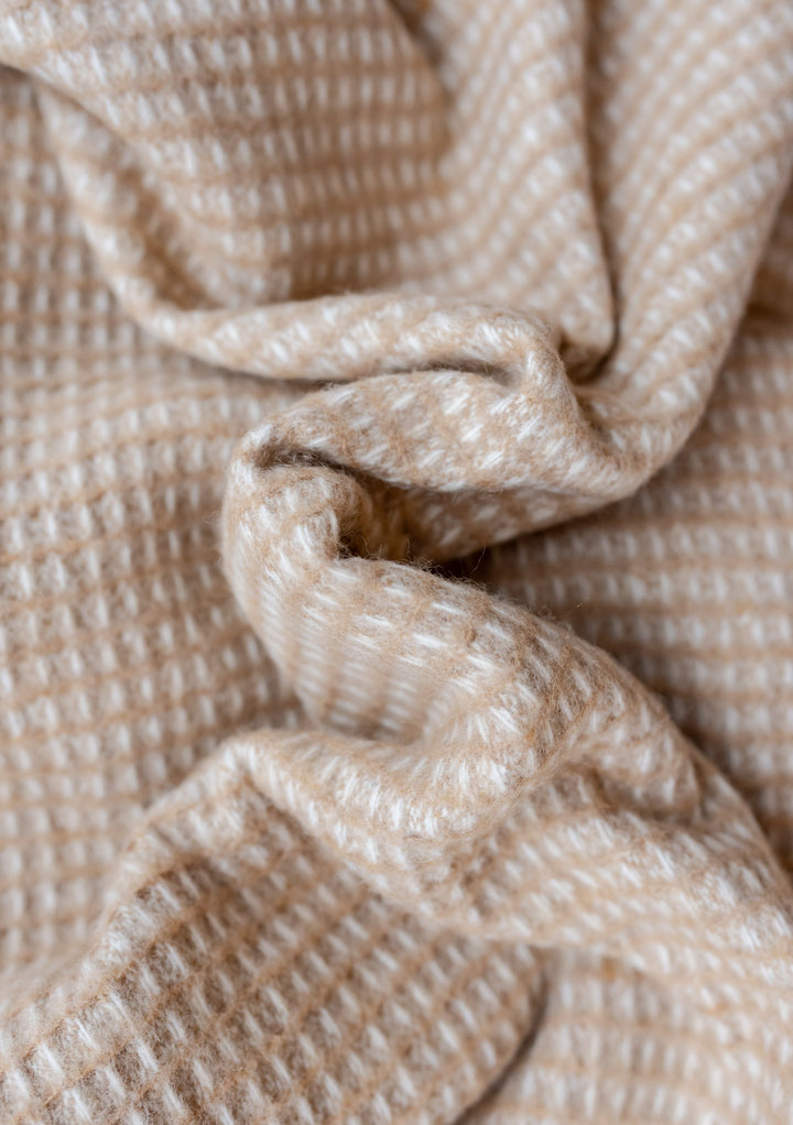 Close-up texture detail of TBCo Recycled Wool Blanket in Neutral Waffle showing soft beige waffle weave pattern