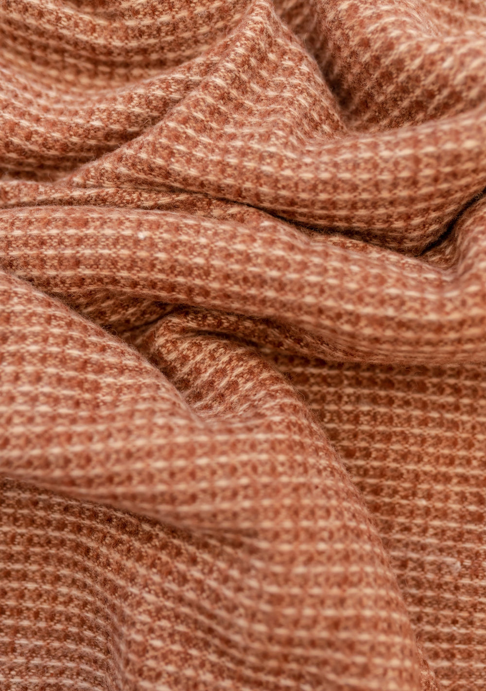 Close-up texture detail of TBCo Recycled Wool Blanket in Rust Waffle showing soft woven pattern in warm terracotta colour