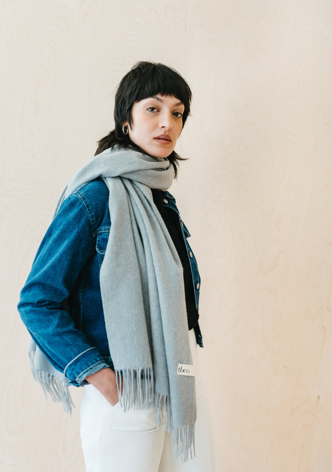 Model wearing TBCo Light Grey Melange Lambswool Blanket Scarf with denim jacket against neutral background
