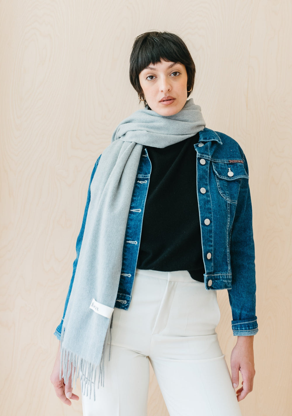 TBCo light grey melange lambswool blanket scarf styled casually with denim jacket and white trousers against neutral backdrop