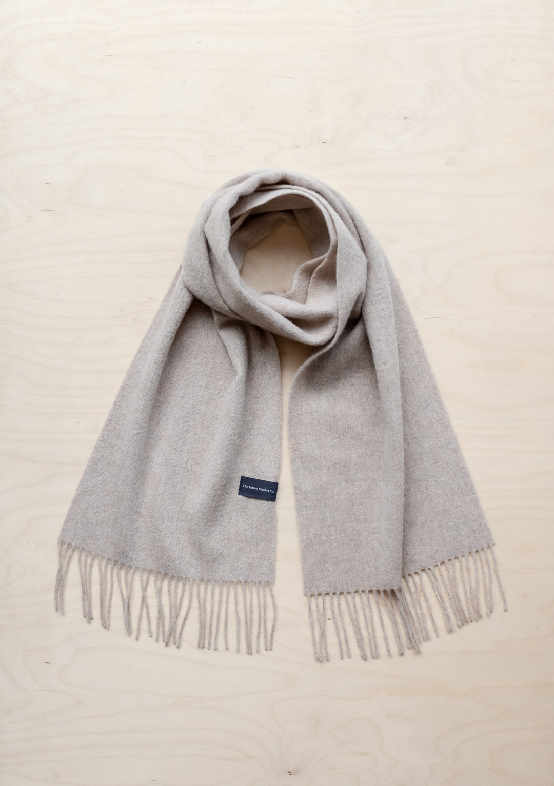 TBCo Men's Lambswool Scarf in Oatmeal Melange with fringed ends, elegantly draped to showcase soft texture and classic design