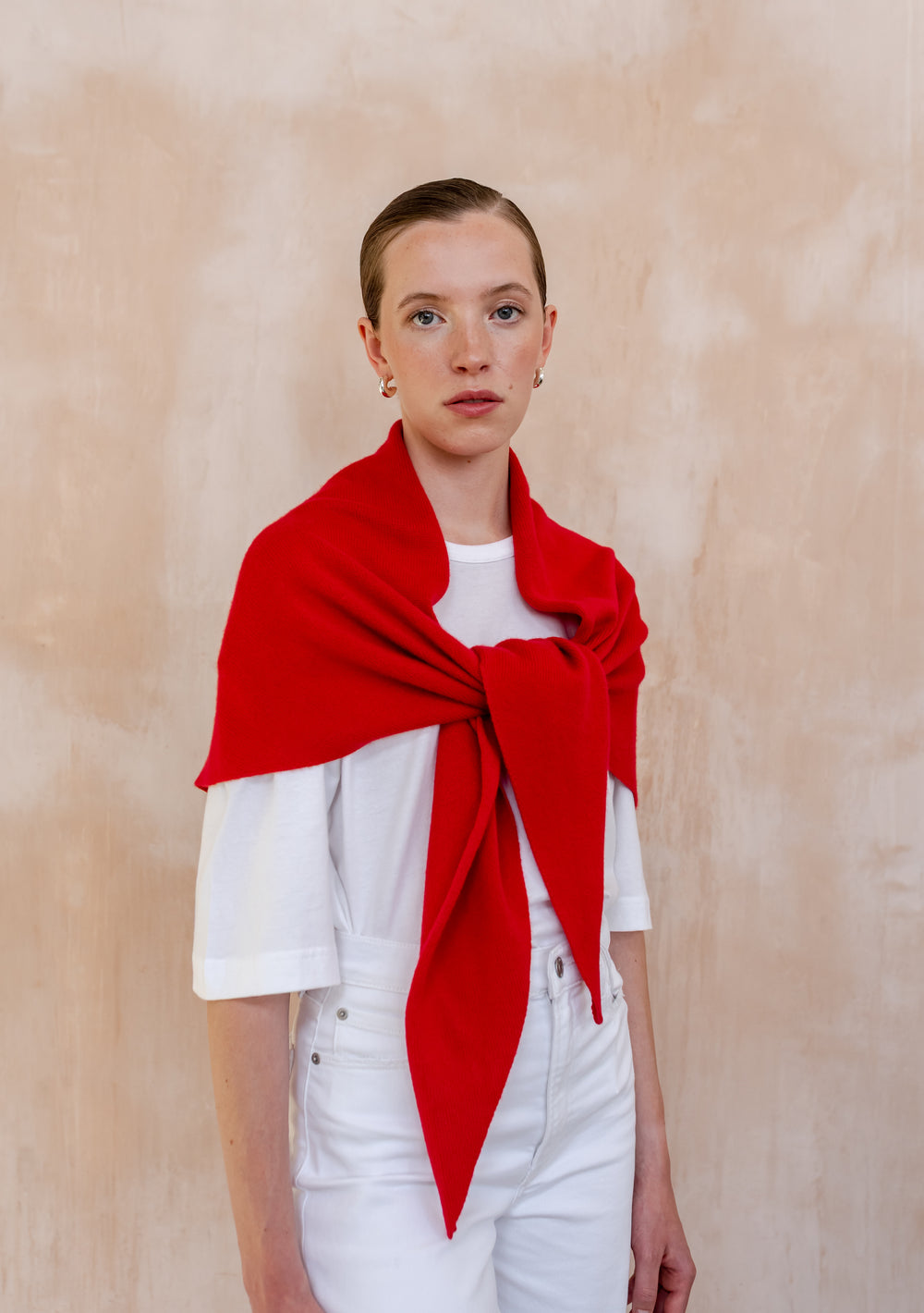 Model wearing a Large Merino Triangle Scarf in Red by TBCo, styled over a white shirt against neutral background