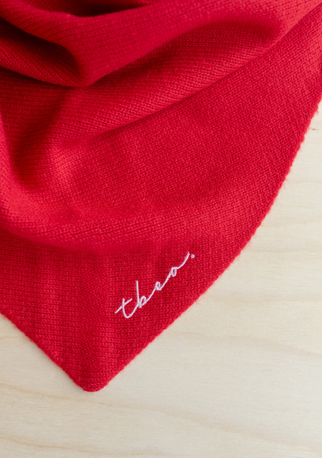 Close-up of the TBCo Large Merino Triangle Scarf in Red showing soft texture and embroidered logo detail.