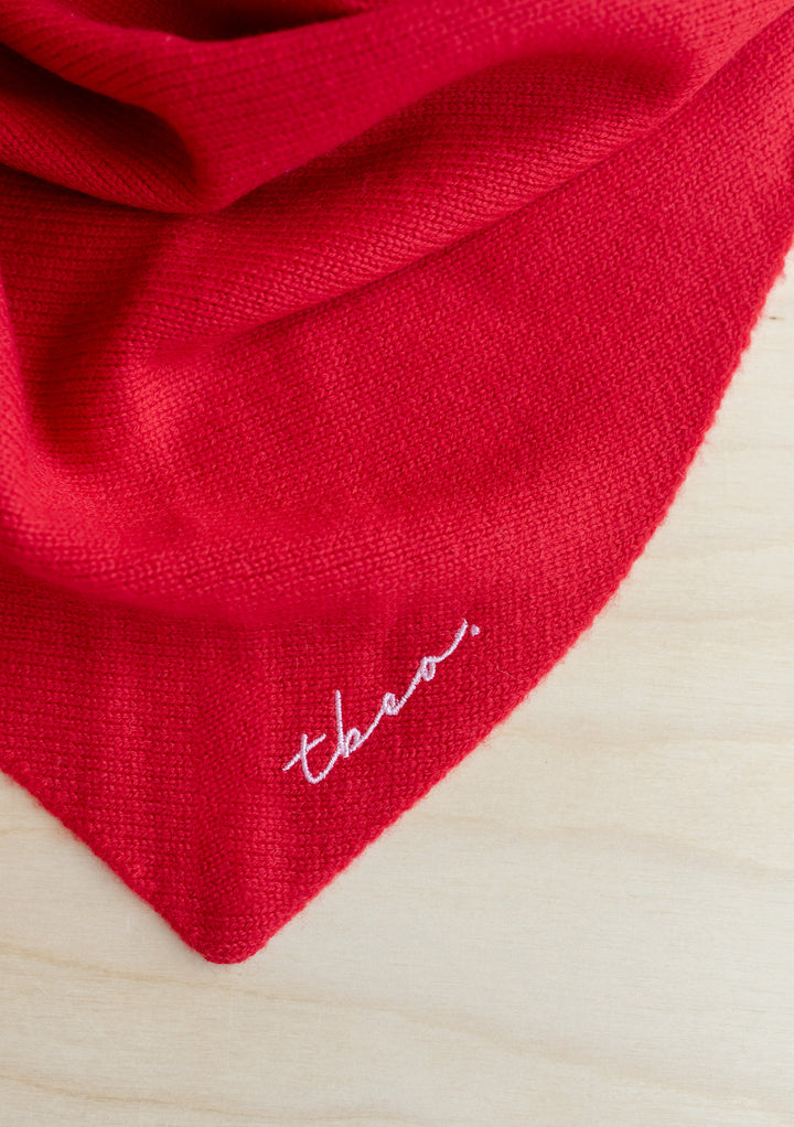 Close-up of the TBCo Large Merino Triangle Scarf in Red showing soft texture and embroidered logo detail.