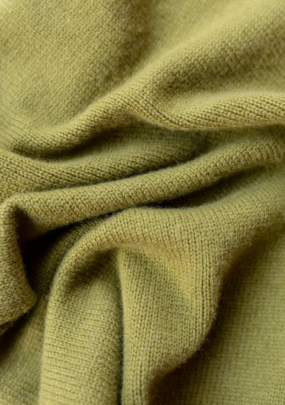 Close-up texture detail of TBCo Merino Triangle Scarf in Olive showing soft knitted wool fabric with gentle folds and draping