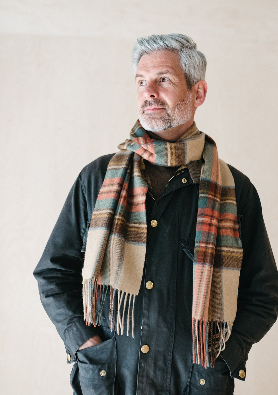 TBCo Stewart Dress Antique Tartan cashmere scarf elegantly draped over dark jacket, showcasing luxurious plaid pattern and fringe