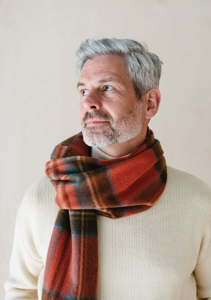 Elegant TBCo Mens Lambswool Scarf in Stewart Royal Antique Tartan shown draped casually with cream knit jumper