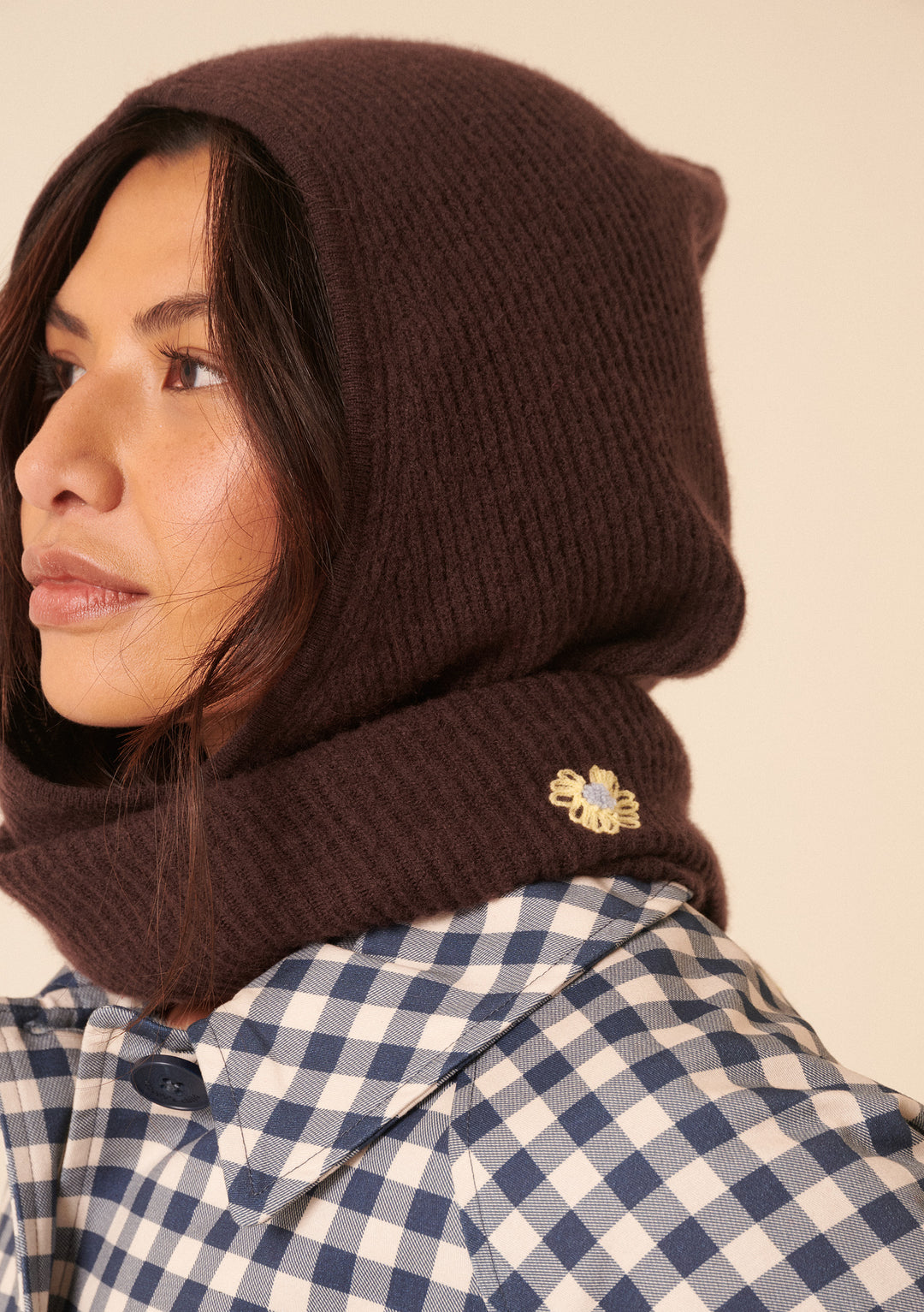 Close-up of woman wearing TBCo NC x TBCo Latte Floral Wool Hood in brown with yellow floral embroidery and checked shirt