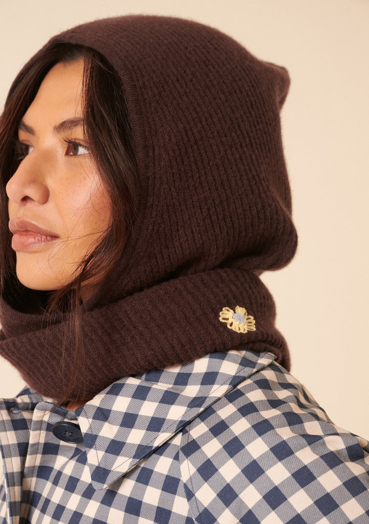 Close-up of woman wearing TBCo NC x TBCo Latte Floral Wool Hood in brown with yellow floral embroidery and checked shirt