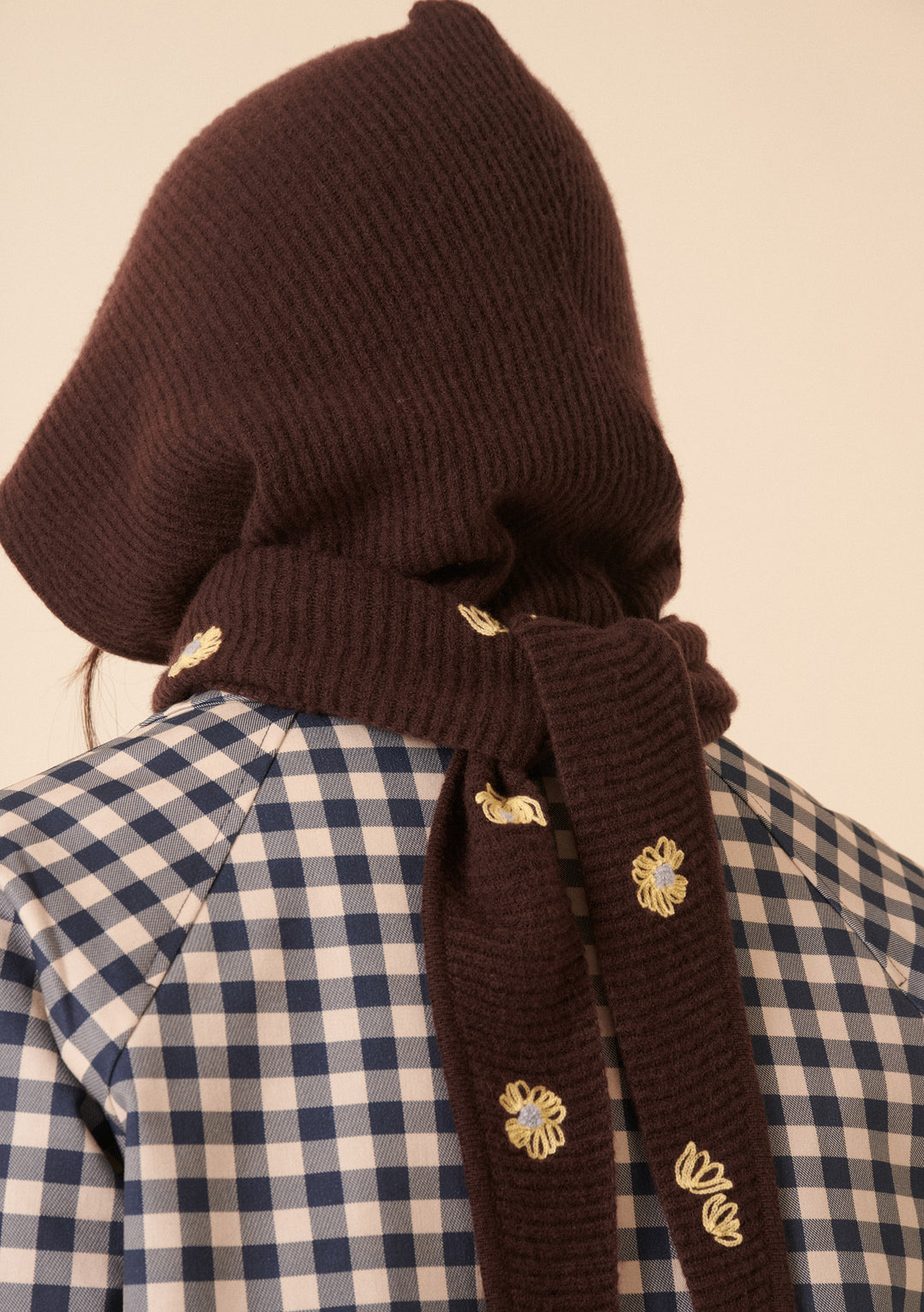 Back view of model wearing NC x TBCo Latte Floral Wool Hood in brown merino with yellow floral embroidery