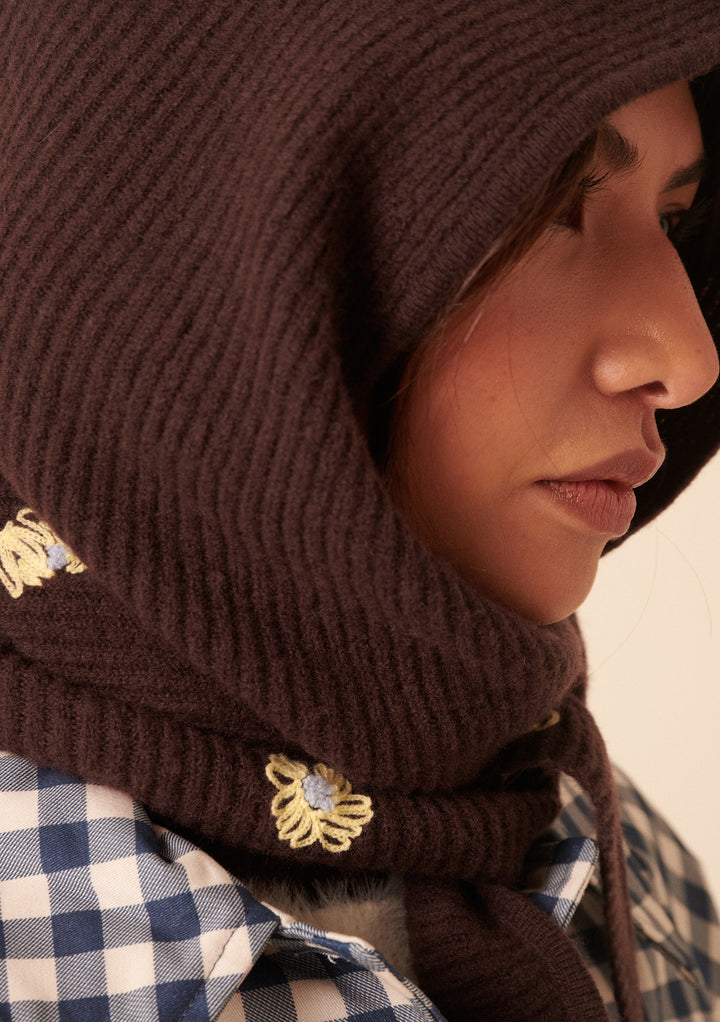 Close-up of woman wearing the brown NC x TBCo Latte Floral Wool Hood with yellow flower embroidery by TBCo