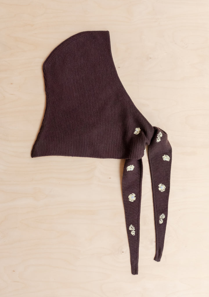 NC x TBCo Latte Floral Wool Hood in brown merino wool with yellow floral embroidery and long ties laid flat on wood background
