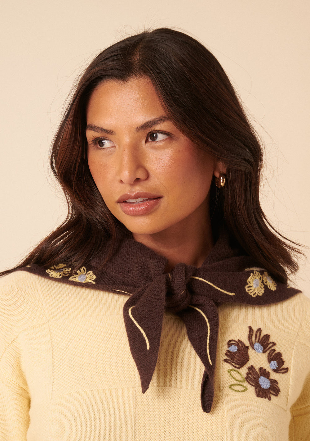 Woman wearing the NC x TBCo Latte Floral Wool Triangle Scarf in brown merino wool with yellow floral embroidery by TBCo