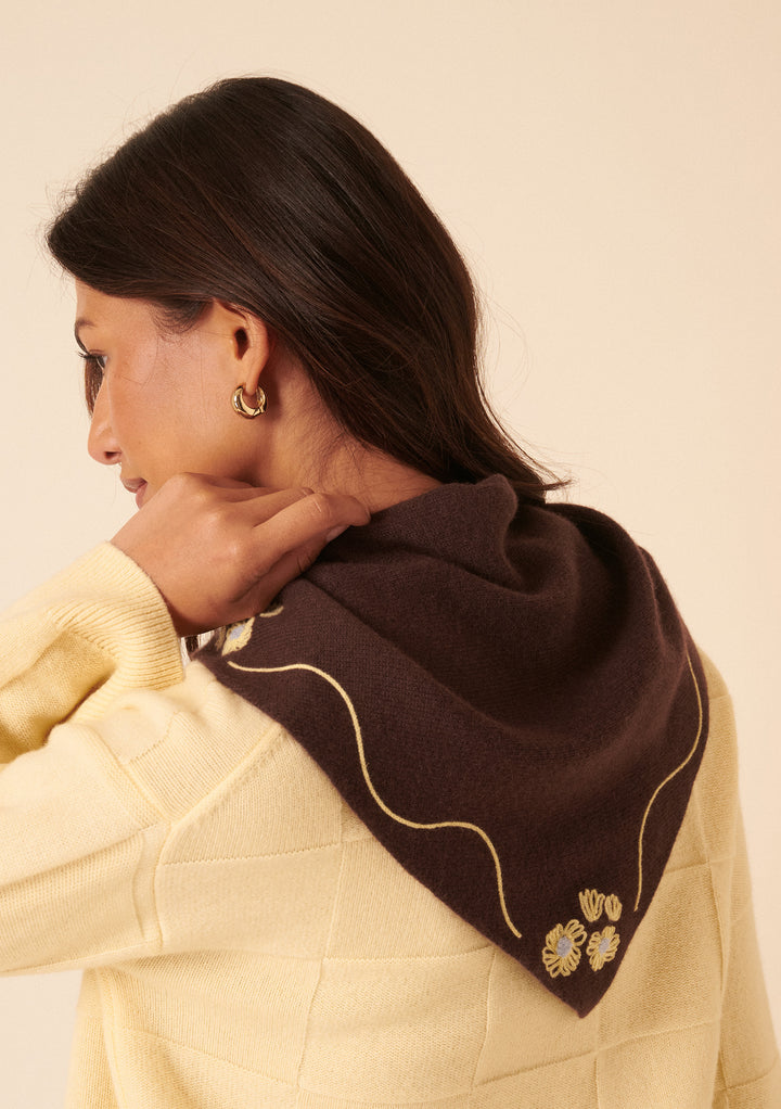 Woman wearing the NC x TBCo Latte Floral Wool Triangle Scarf in brown merino wool with yellow floral embroidery by TBCo