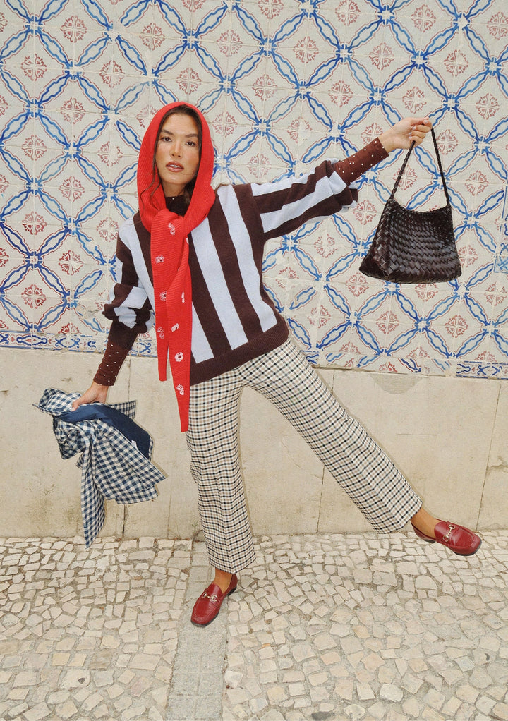 Woman wearing NC x TBCo Red Floral Wool Hood styled with striped jumper and checked trousers against patterned wall