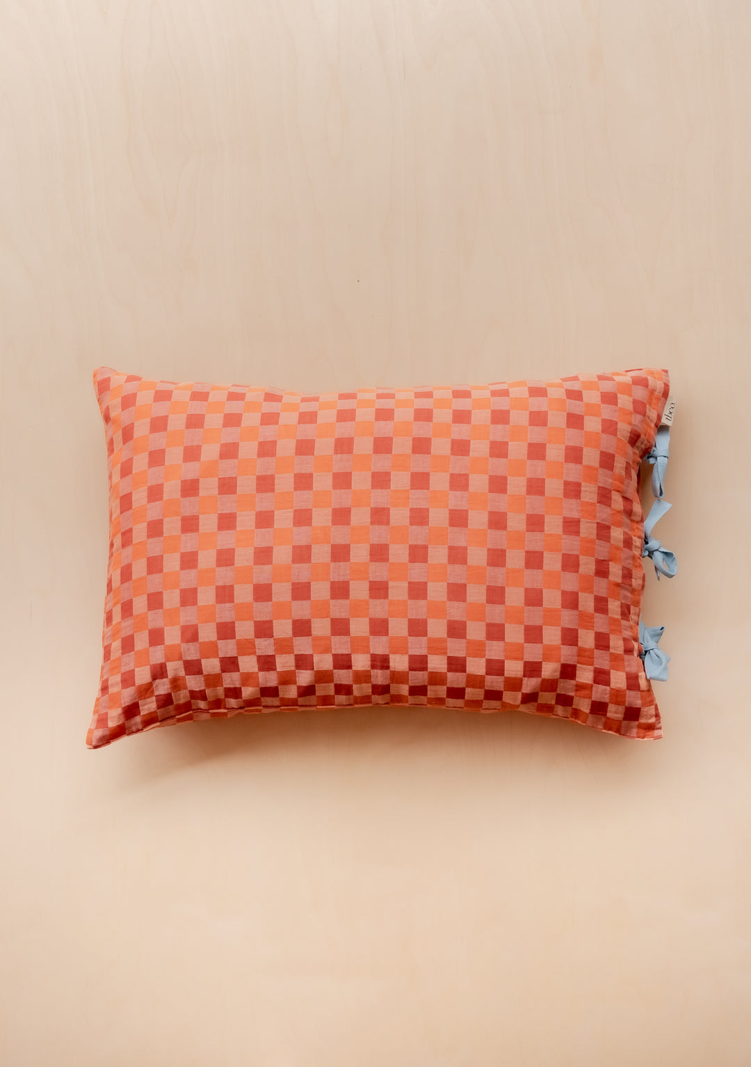 TBCo cotton pillowcase in apricot checkerboard pattern with blue ties, shown against neutral backdrop