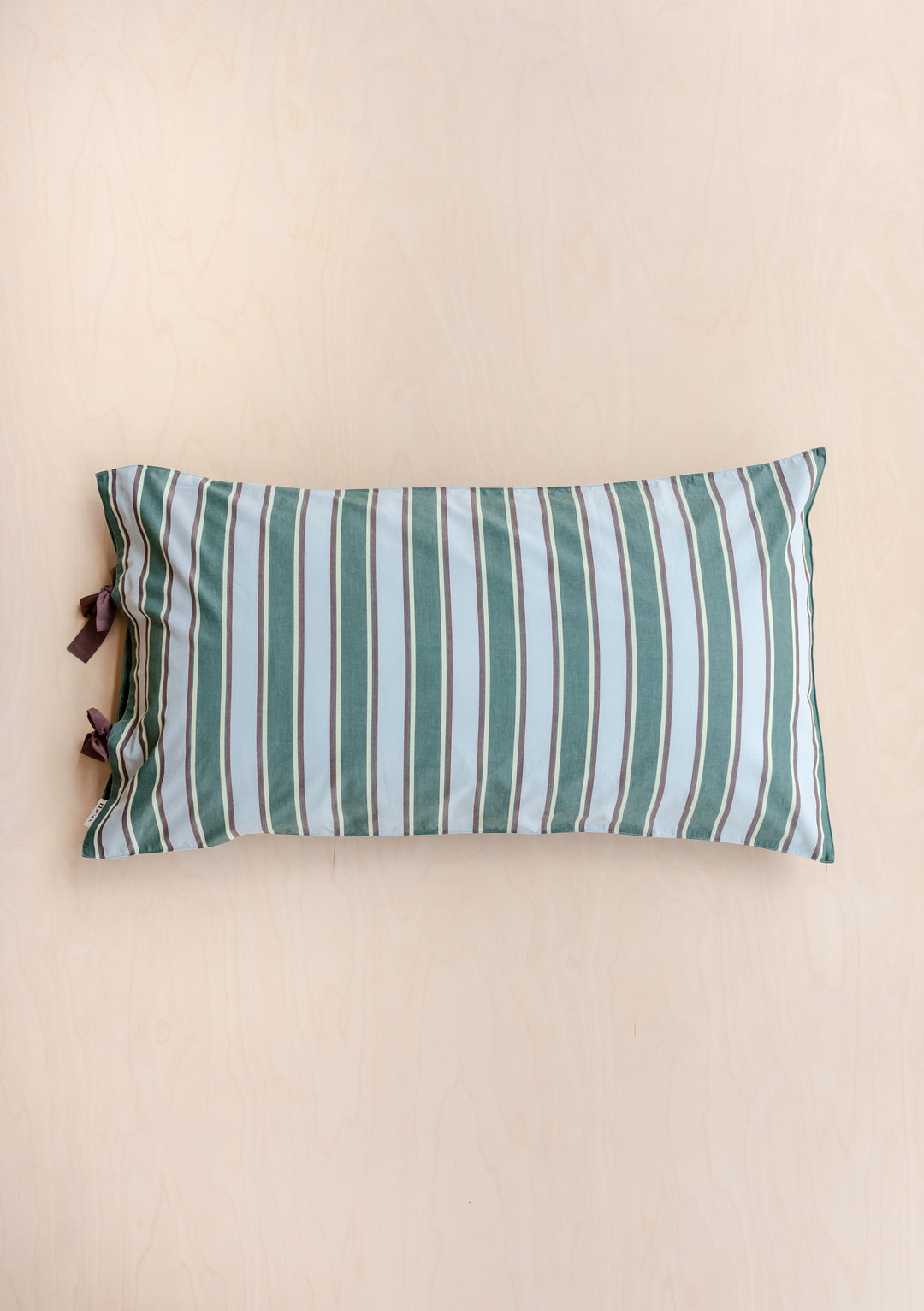 Pair of Cotton Pillowcases in Blue Stripe by TBCo featuring green tailored stripes and delicate tie closures on a light background.
