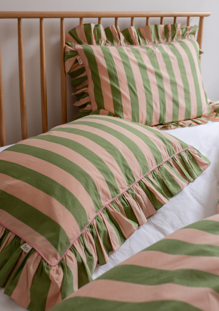 TBCo cotton pillowcases with green and white stripes and delicate ruffled edges, displayed on wooden bed frame