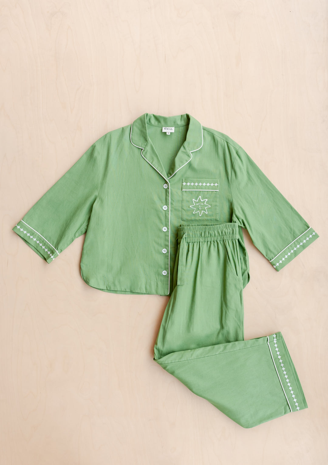 TBCo Cotton & Linen Pyjamas in green with embroidered sun motif and sleeve details, displayed flat on beige background